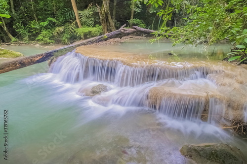 Beautiful silky water cascade flowing on cliff rocks around with blue-green water and green forest background  Erawan Waterfalls  1th step  Kanchanaburi  west of Thailand.