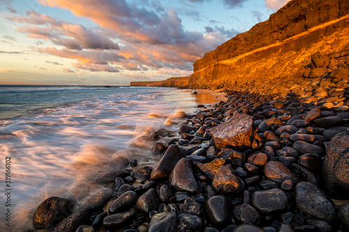 Beautiful sunset at the ocean beach under a rocky cliff, cliff coast south of El Cotillo, Canary Islands, Fuerteventura photo