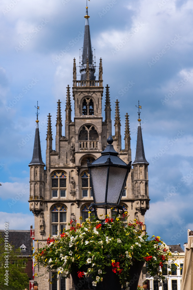 Obraz premium Eine mit Blumen geschmückte Laterne und das Rathaus von Gouda/NL im Hintergrund