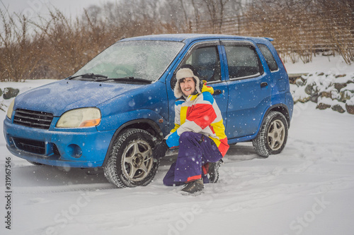 Winter accident on the road. A man changes a wheel during a snowfall. Winter problems