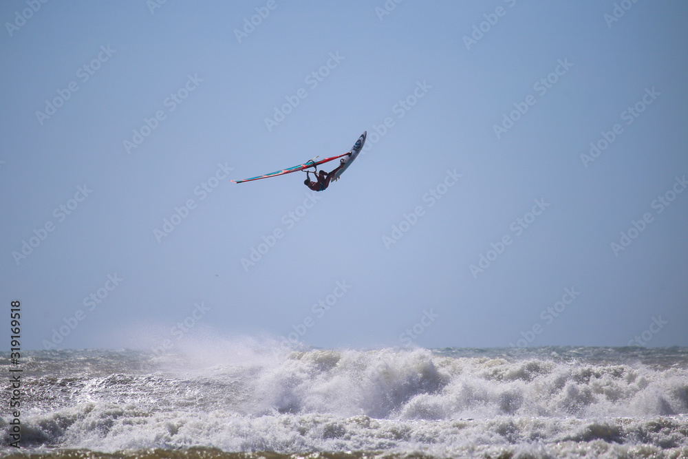 A flying windsurfer above the turquoise water A flying windsurfer above the turquoise water