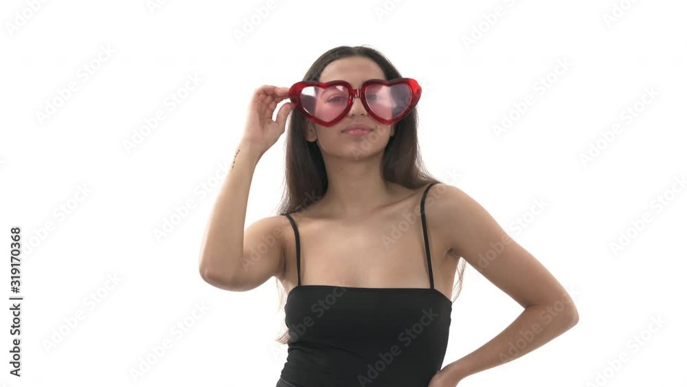 Young cheerful woman wearing heart shaped glasses and sending air kisses. Girl posing to camera in flirting manner Young cheerful woman wearing heart shaped glasses and sending air kisses. Girl posing to camera in flirting manner