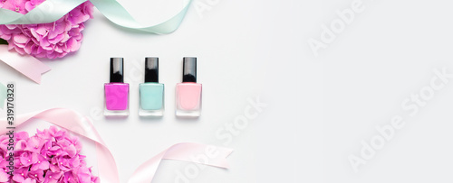 Decorative cosmetics, nail polish. Set of different varnishes for manicure nails on light background with flowers of pink hydrangea top view Flat lay mock up. Female cosmetics. Beauty blogger concept photo