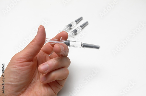 Generic prefilled vaccine syringes. Man’s hand holding vaccine syringe.