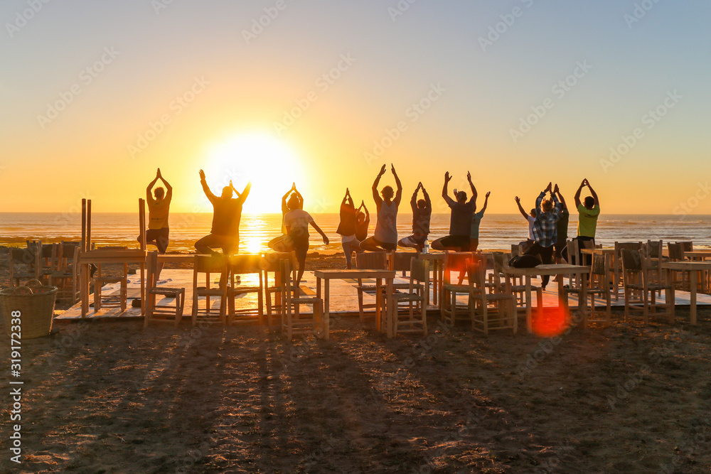 Group yoga on the beach at sunset