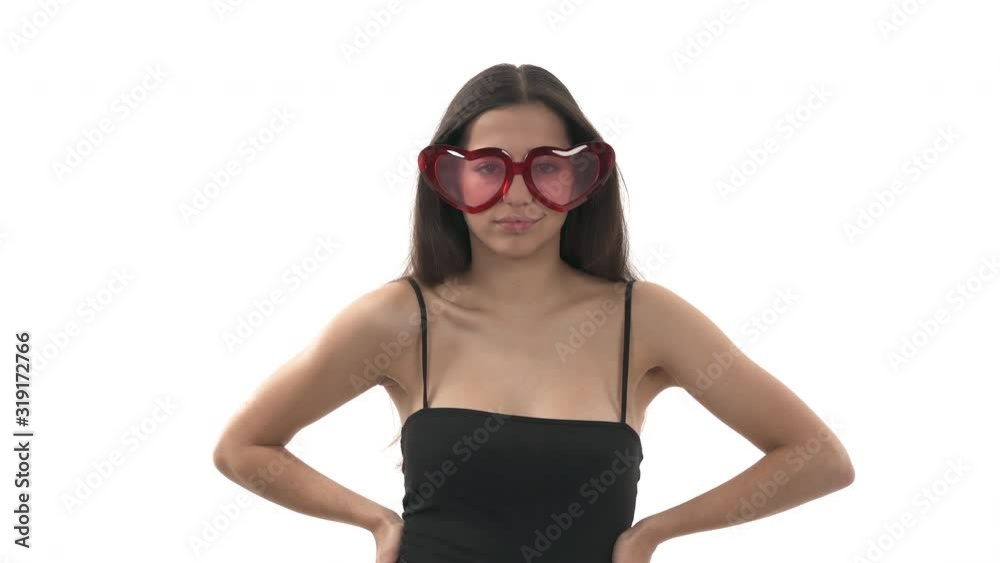 Close-up portrait shot of a young cheerful woman wearing heart shaped glasses and posing to camera. Valentine's day concept Close-up portrait shot of a young cheerful woman wearing heart shaped glasses and posing to camera. Valentine's day concept