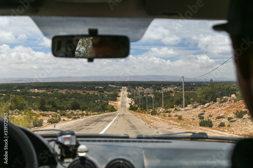 View through the windshield on the road, the mountains and the cloudy sky