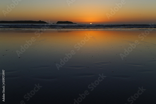 Wet sand at low tide on a sunset background