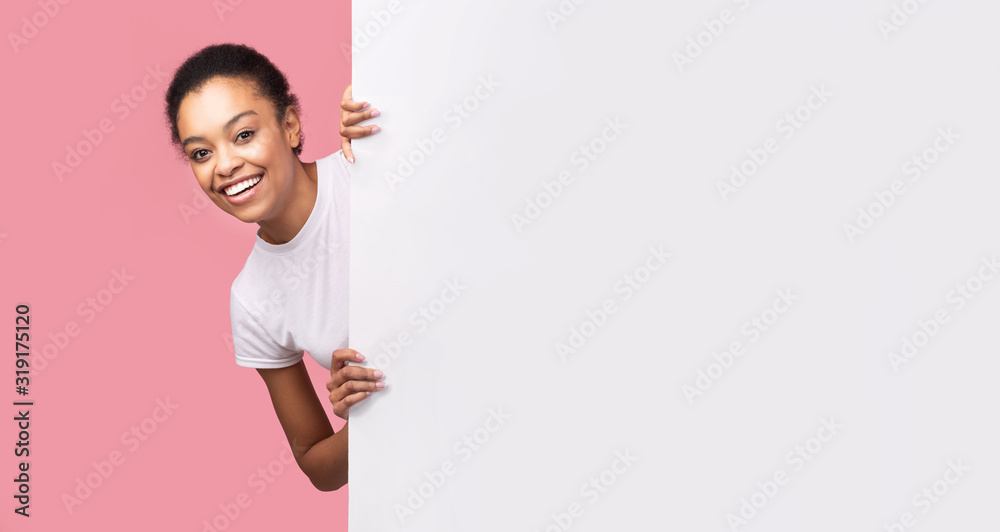 Girl Peeking Out Of Blank Poster Standing Over Pink Background Girl Peeking Out Of Blank Poster Standing Over Pink Background
