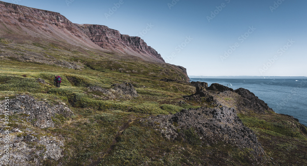 Arctic landscape of Disko Bay in Greeland in Summer. Blue Sky and green meadows. Arctic Circle Trail with temple mountains. Disko Island and Village of Qeqertarsuaq.