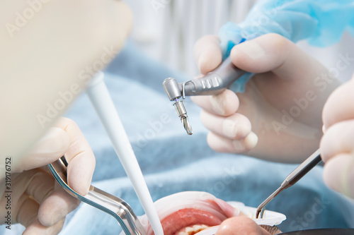 Dentist's hands in sterile gloves close-up, with an implantation tool.