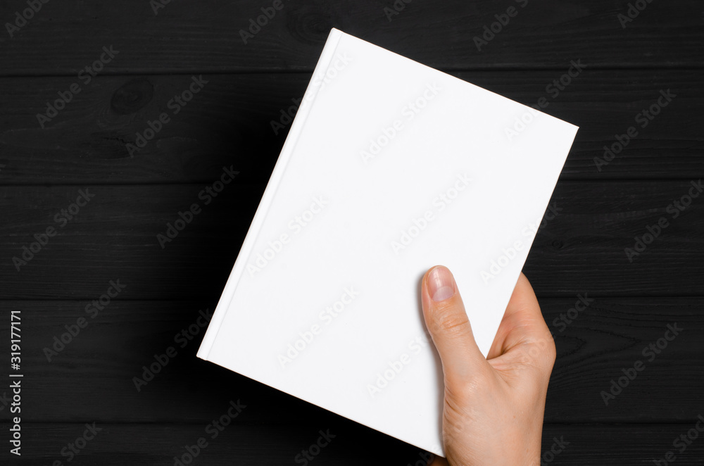 Men's hands holding closed book with blank cover on light background Men's hands holding closed book with blank cover on light background