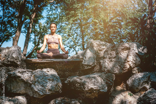 Blessed with love. Full-length shot of caucasian woman sitting in Easy Seated pose  Sukhasana while practicing yoga outdoors  in a garden. Healthy lifestyle and relaxation concept
