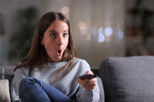 Surprised woman watching tv at home in the night photo