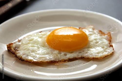 Fried egg close up in white plate. Breakfast food. Sunny side soft fried egg.