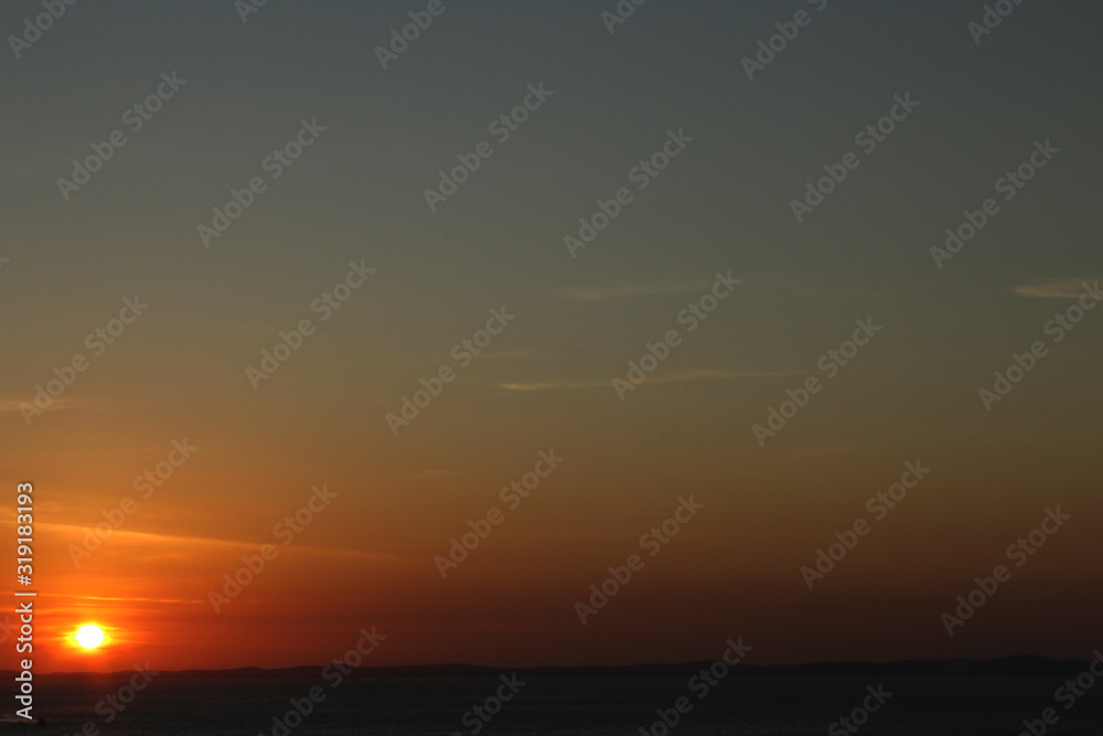 Serene twilight with orange and blue sky with thin horizon line