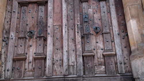 Close-up of closing two old wooden doors with metal handles in ancient medieval Catholic church. For religion, histotic, architecture background.