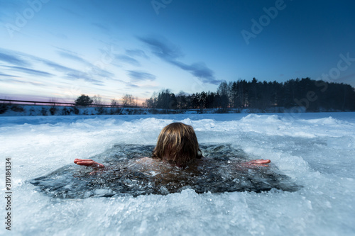 Young man with beard swims in the winter lake photo