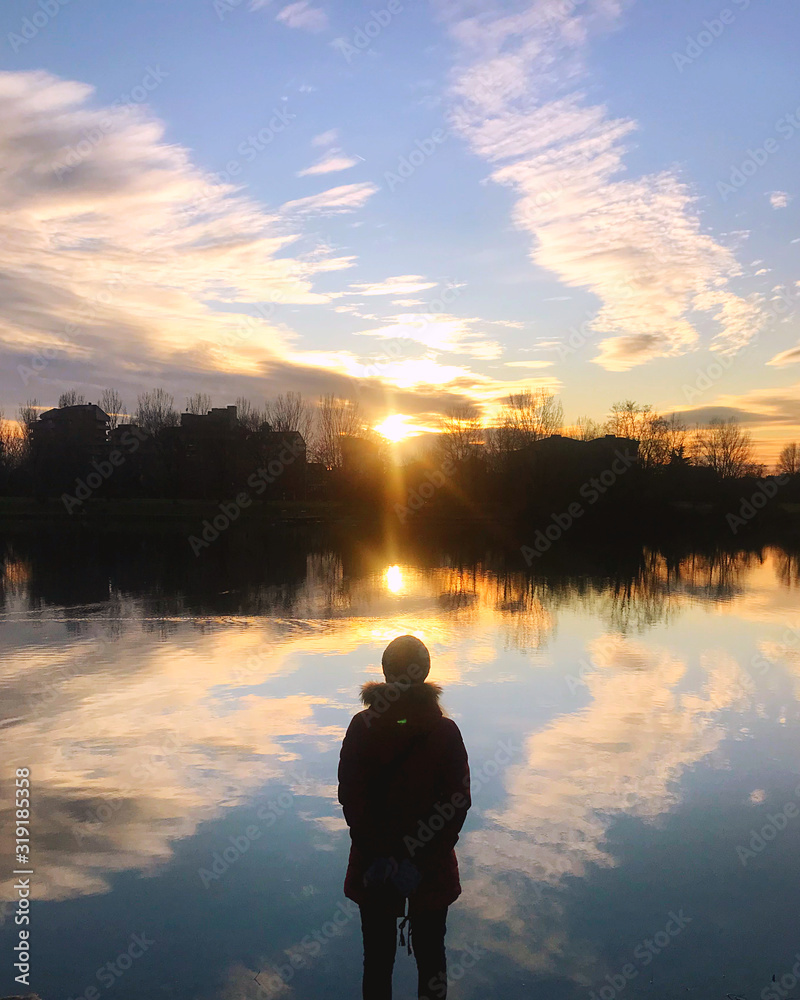 Fototapeta premium Una donna persierosa guarda la luce del sole, cielo tramonto. Fede, Speranza, Amore.