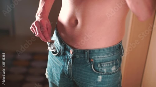 A man without a T-shirt takes a condom from his pants