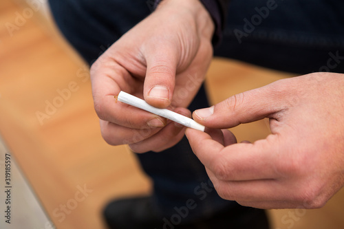Closeup on the hands of a man holding a hand-wrapped cigarette. And he s getting ready to smoke it.