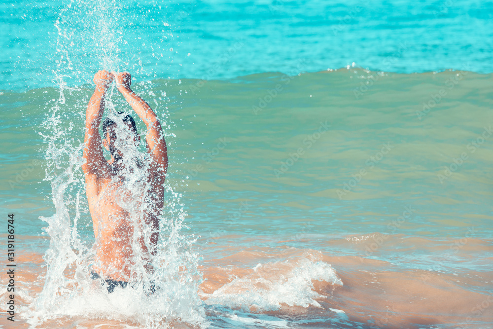 Young man splashing in the sea. Vacations.