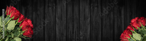 Flowers background banner panorama - Bunch bouquet of red roses on dark black rustic wooden texture, with space for text