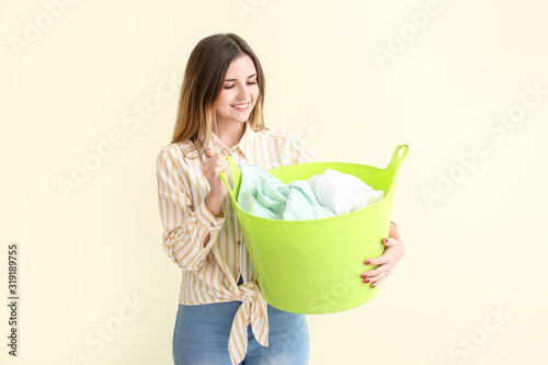 Beautiful young woman with laundry on color background