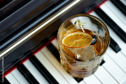 Old fashioned cocktail with orange and cherry on the piano keys.