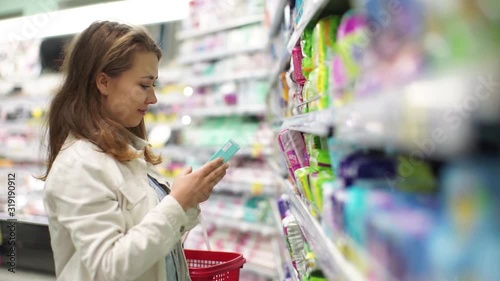 Beautiful woman buys cosmetics in a store.A girl in a cosmetics store. Beautiful woman shopping in a supermarket.The girl checks the composition of the product.Girl in shop of household chemical goods