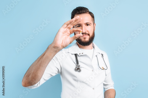 image of a doctor's hand showing a single capsule on a light blue background