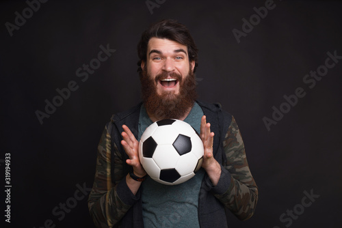 I caught the ball. Young bearded hipster is holding a soccer or football ball.
