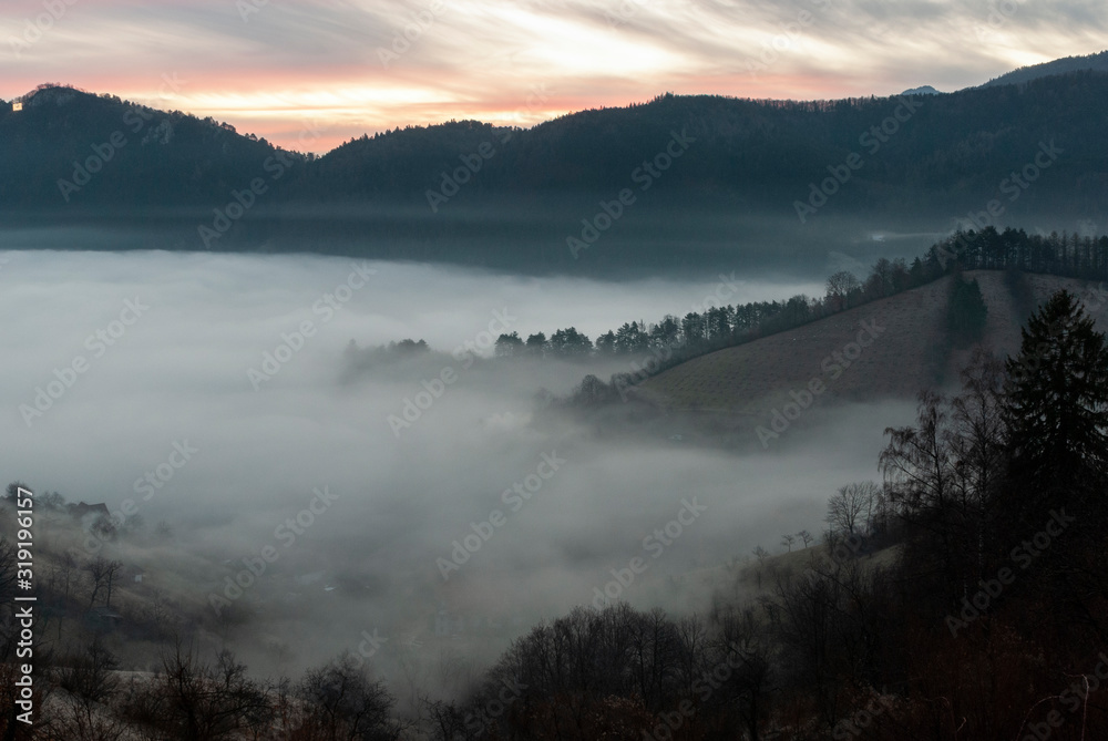 A moment before sunrise in a mountainous area where the mist is rising from the city valley.