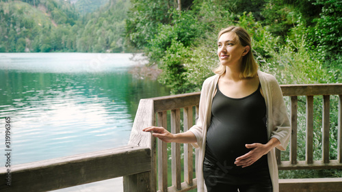 Fotografía Beautiful pregnant woman near a mountain lake in the forest.