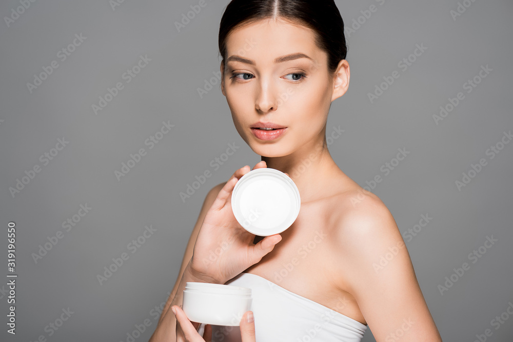 attractive girl holding plastic container with face cream, isolated on grey attractive girl holding plastic container with face cream, isolated on grey