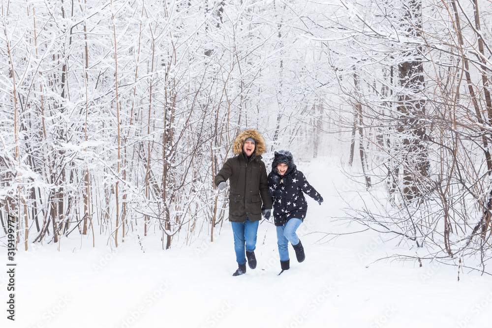 Happy couple walking through a snowy forest in winter