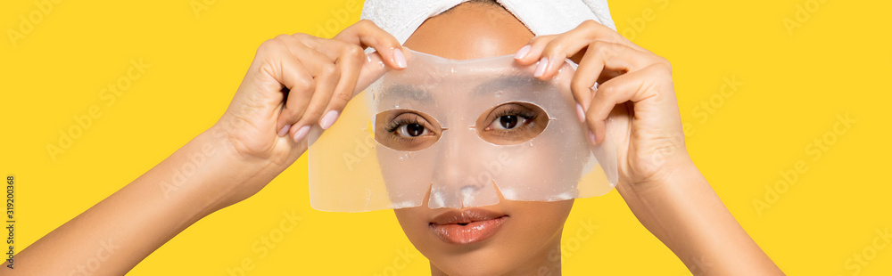 Φωτογραφία panoramic shot of attractive african american girl with towel on head applying h