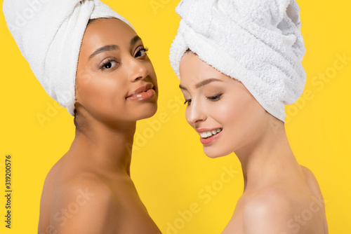 cheerful multicultural girls with towels on heads, isolated on yellow