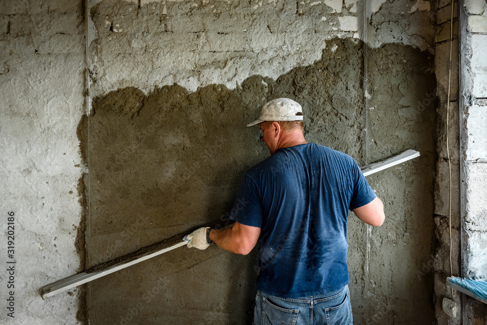 Construction worker plastering wall with leveler. Construction worker plastering wall with leveler.