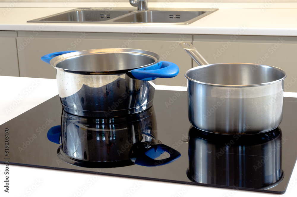 two stainless steel cooking pots on induction cooking plate modern helper with low energy consumption and high efficiency black glass on white kitchen countertop new kitchen with kitchen sink faucet two stainless steel cooking pots on induction cooking plate modern helper with low energy consumption and high efficiency black glass on white kitchen countertop new kitchen with kitchen sink faucet