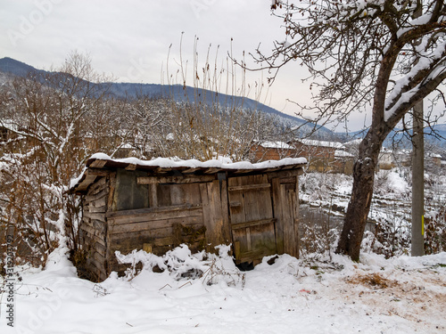 Old wooden log shed at the Vidima riverbank at the winter Bulgarian Fore-Balkan village of Debnevo, Central-North Bulgaria photo