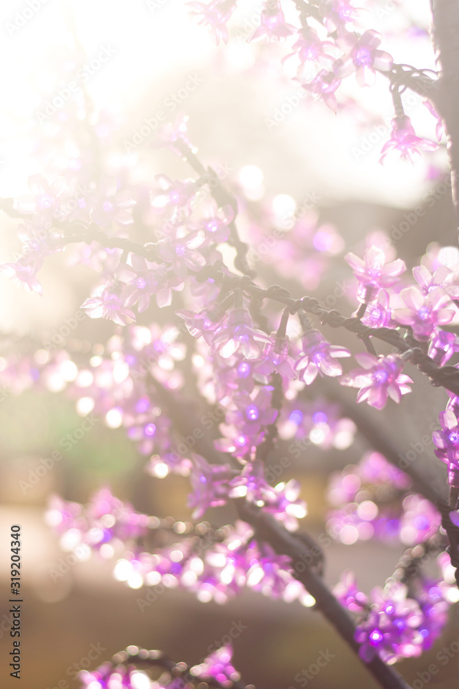 A branch of small artificial pink flowers made of glass. Sakura branch. Sunny day. Soft selective focus. Close up.