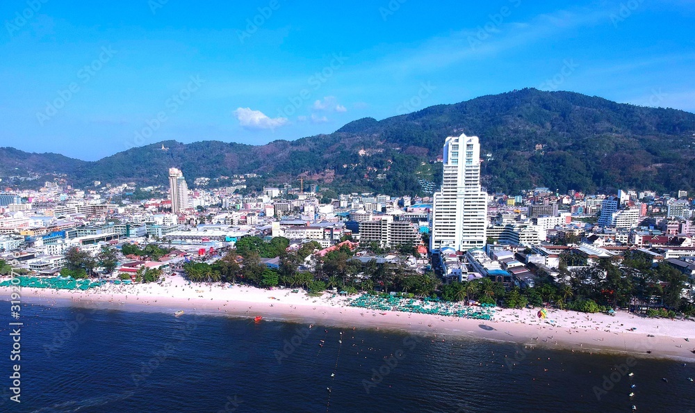 Panoramic View of Patong Beach buildings boats parasailing jetski people on the beach and beautiful blue skies long tail boats