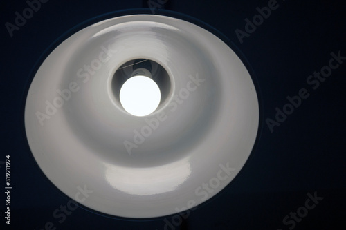 a bright white lamp shines on the ceiling in a dark room