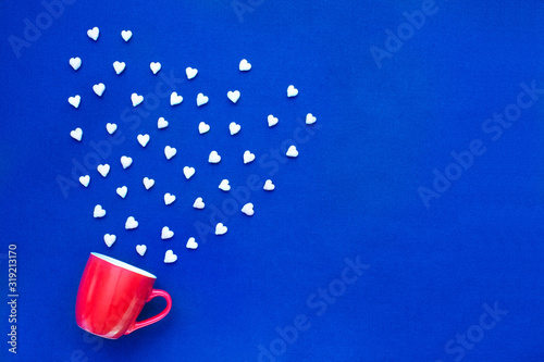 Red coffee cup with heart shaped candies on a blue background. Design for greeting cards, invitations, posters, menu and website.