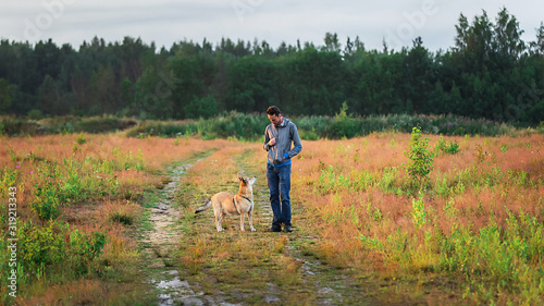 Young guy training dog in countryside at nature