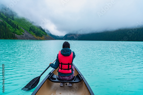 Woman paddling a canoe through Lake Louise