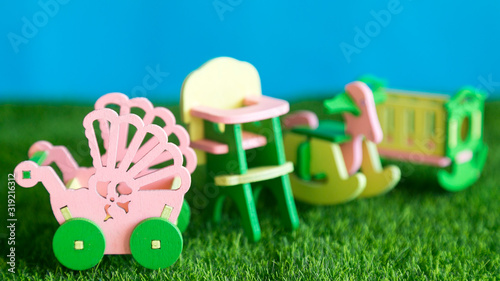 Children's furniture, crib, high chair, stroller on the green grass. Conceptual photography Childhood in furniture.