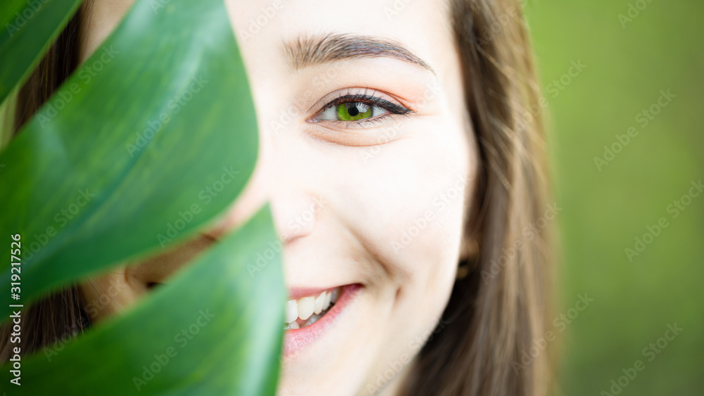 Beautiful young woman with perfect skin and natural make up. Teen model with green leaves. SPA, skincare and wellness. Close up, selective focus Beautiful young woman with perfect skin and natural make up. Teen model with green leaves. SPA, skincare and wellness. Close up, selective focus