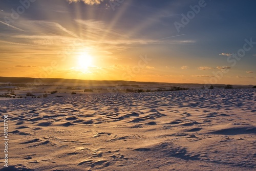 Sonnenstrahlen in der verschneiten Winterlandschaft photo